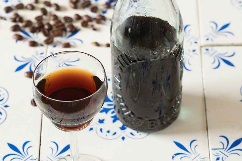 Glas en fles met koffielikeur op tegeltableau met koffieboontjes 